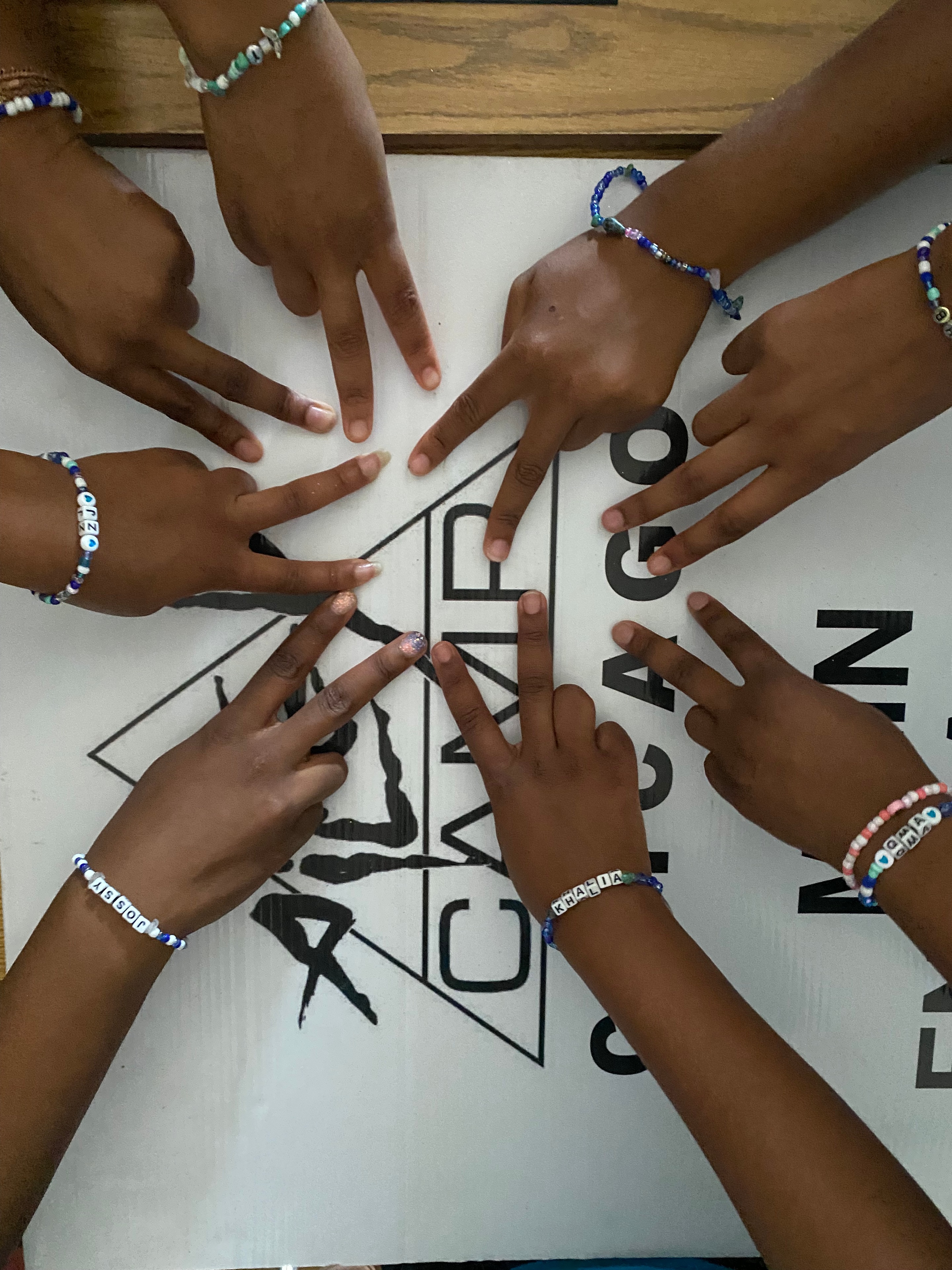 Participants showing their handmade bracelets with hands gathered over shared artwork.